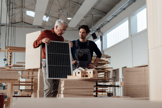Businessman with colleague discussing over solar panel in industry