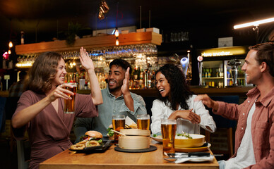 Young multiracial group of friends in casual clothing celebrating at restaurant