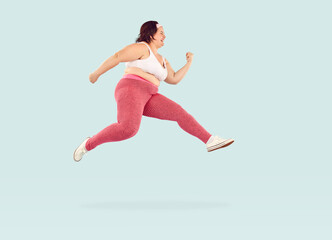 Fototapeta na wymiar Full length photo of young fat overweight woman wearing sportswear jumping and hurrying to the gym to do exercises isolated on studio blue background. Workout sport, fitness and body positive concept