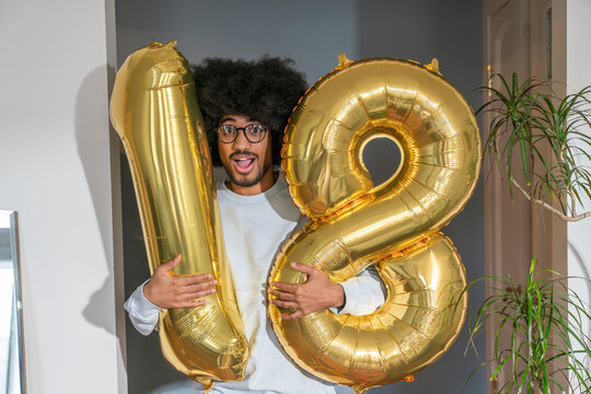 Surprise man holding 18 number balloon at home