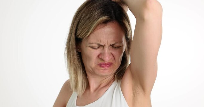 Portrait of woman sniffing armpits and disgusted by smell. Bad odor and diseases of body