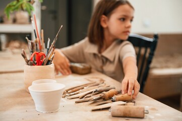 Different tools on the table. Little girl is learning how to do pottery in the workshop