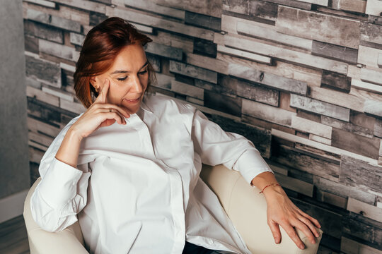 Image of thinking young lady. Sad woman sitting on sofa at home deep in thoughts, thinking about important things. Thinking business woman. Distracted from work worried young woman sitting on couch