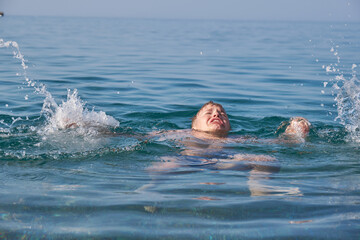 The child is drowning in the sea, screaming and waving his arms.