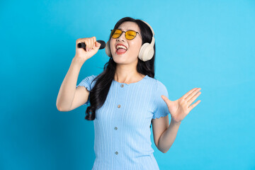 Portrait of smiling asian woman posing on blue background