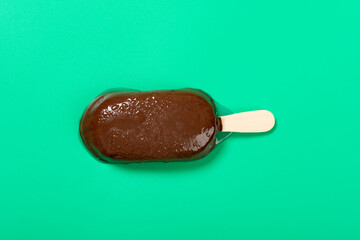 chocolate outer with milk and blueberry flavors popsicle starts melting on green background