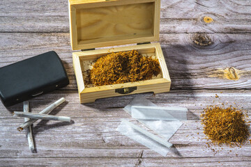 wooden box with rolling tobacco, rolled cigarettes, cigarette papers and filters