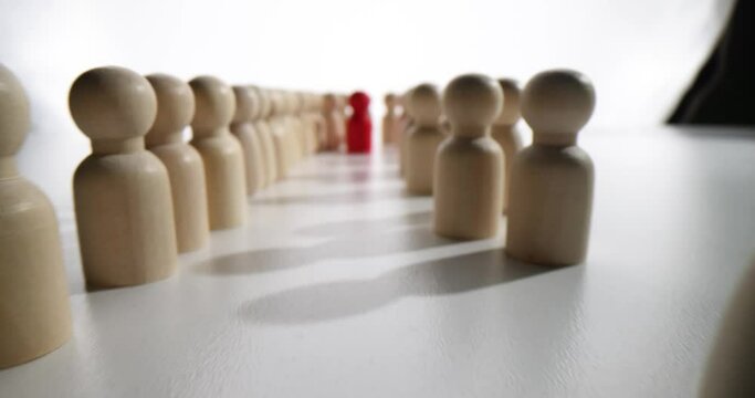 Red wooden figurine of human in crowd of figurines. Leadership career skills and development tools