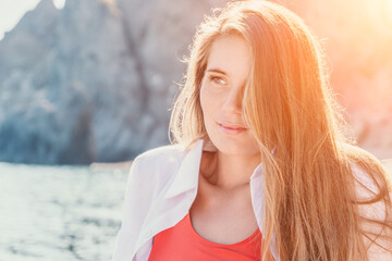 Young woman in red bikini on Beach. Girl lying on pebble beach and enjoying sun. Happy lady with long hair in bathing suit chilling and sunbathing by turquoise sea ocean on hot summer day. Close up