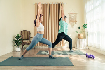 Two Asian women body size different in sport wear doing training yoga at home together. Healthy lifestyle and workout at home concept..