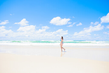 Fototapeta na wymiar 青い空と海の前を歩くビキニの白人女性