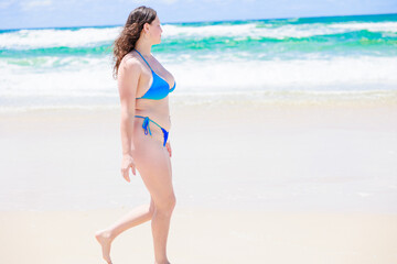 Fototapeta na wymiar ビーチを歩く水着姿の白人女性