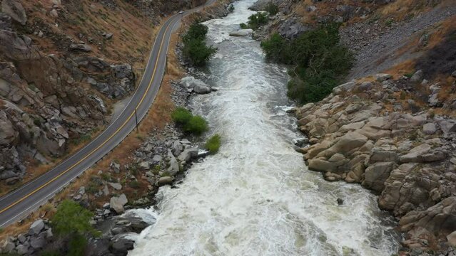quick aerial dolly down the kern river on highway 178 from lake isabella dam in bakersfield during a raging flood with quick turbulent water rushing hard and covering trees