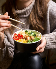 Clean eating diet concept. Chicken bowl with avocado in take out paper container in hands of woman having a lunch break. Close up