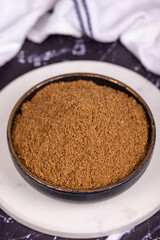 Coriander powder on dark background. Powdered dried coriander in bowl. Spice concept. Close up