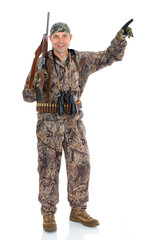 Full length portrait of happy duck hunter with a rifle and binoculars points to something to the side, isolated on white background. Fifty-year-old man in hunting uniform smiling and posing in studio.