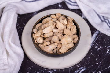 Ginger root on dark background. Ginger root in wooden bowl. Mixture of spices and dried herbs. Spice concept