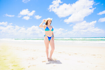 Fototapeta premium 真夏の海と帽子をかぶった青い水着の白人少女（全身）
