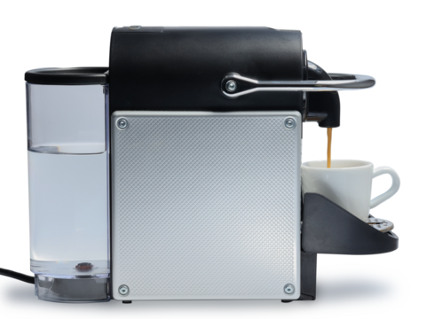 Home semi professional automatic coffee capsule metal machine side view pouring coffee into a cup for making coffee drinks on the bar at home isolated clipping path on white background with shadow.