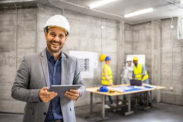Portrait of an experienced architect with hard hat holding digital tablet computer while civil...