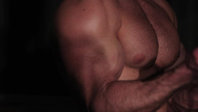 Biceps muscle pumping, athletic muscular guy trains arm muscles
