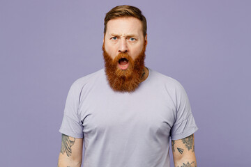 Young sad indignant furious redhead bearded man he wear violet t-shirt casual clothes looking...