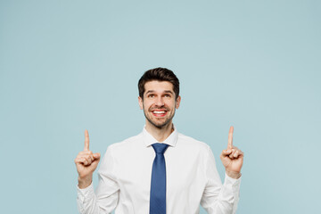 Young fun employee business man corporate lawyer in classic formal shirt tie work in office point index finger overhead on area mock up isolated on plain pastel light blue background studio portrait