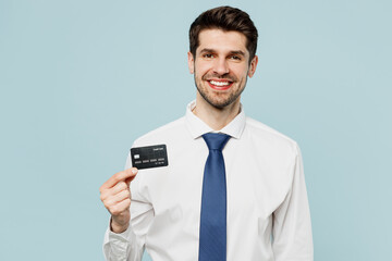 Young fun employee business man corporate lawyer wear classic formal shirt tie work in office hold in hand mock up of credit bank card isolated on plain pastel light blue background studio portrait.