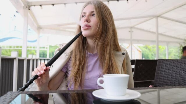 girl woman smoking hookah in terrace restaurant sitting with coffee cup on table,typing message on phone.female with cold sore herpes hpv virus on lips 4k.hookan man putting coal cubes on tabaco bowl