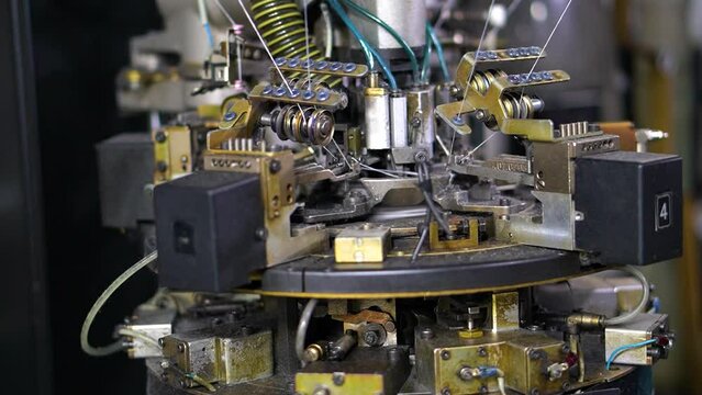 Close-up parts of the machine with threads producing garments (socks), the Production process in a garment factory, automated process, manufacture of clothing (Pakistan)