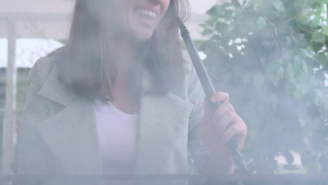 girl woman smoking hookah in terrace restaurant sitting with coffee cup on table,typing message on phone.female with cold sore herpes hpv virus on lips 4k.hookan man putting coal cubes on tabaco bowl