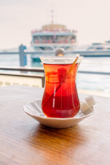 A traditional cup of Turkish tea with the Golden Horn and the ferry in the background. A traditional cup of Turkish tea in a cafe on the Galata Bridge across the Golden Horn Bay.