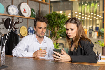 Friends drinking cocktail looking at the mobile phone