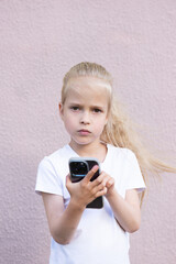 Little blonde girl with a smartphone in her hands.