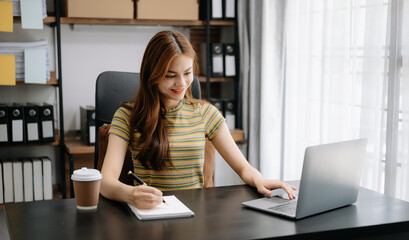  Beautiful Asian business woman typing laptop and tablet Placed at the table at home office..