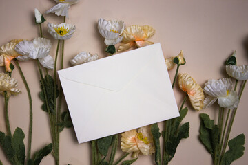 A cream envelope over the flowers on a pink background. 