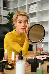 Charming young gay man blogger recording make up tutorial, live streaming at home. LGBTQ lifestyle, influencer, blogger