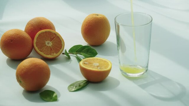 The slow-motion video demonstrates the process of pouring natural orange juice, which is produced from fresh citrus fruit. This juice is a selective natural pleasure that promotes health.