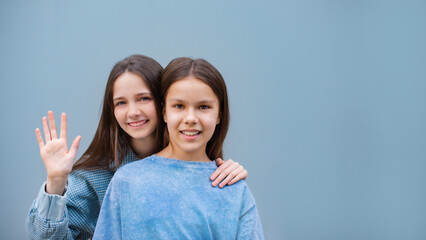 two cheerful teen girls hand on shoulder toothy smile look camera isolated on blue color wall background