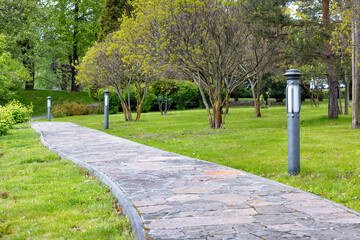 A stone-paved garden path runs diagonally across the spring garden.