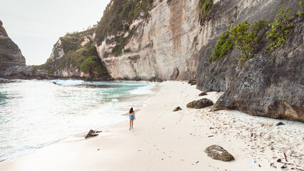 Podróżnik idący po pięknej plaży Diamond, na Indonezyjskiej wyspie Nusa Penida, plaża, skały...