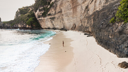 Podróżnik idący po pięknej plaży Diamond, na Indonezyjskiej wyspie Nusa Penida, plaża, skały...