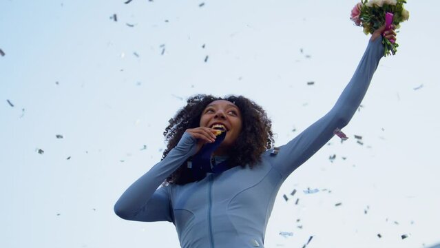 Young African-American Female Athlete Celebrates a Win on a podium, receives a gold medal