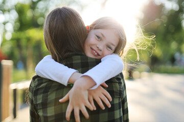 Happy child girl hugging her mother in the rays of the sunset.