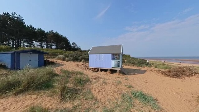 Push in shot towards a traditional wooden beach hut or surf shack on Hunstanton's south beach. Captured on a bright and sunny morning