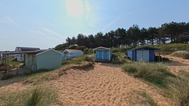 Panning shot of Hunstanton South Beach and the traditional wooden beach huts or surf shacks. Captured on a bright and sunny morning