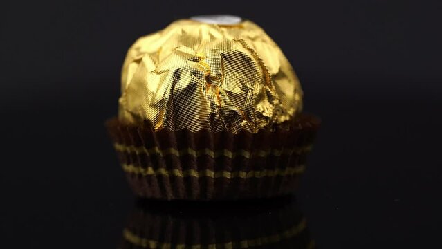 Dnipro. Ukraine 05.03.2023: Ferrero Rocher chocolate and hazelnut confectionery balls. Ferrero Rocher is a chocolate sweet made. Chocolate candies in a gold wrapper. Luxurious Design