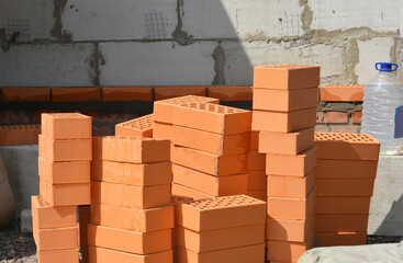 Pile of clay bricks and bottle with plasticizers for concrete. Plasticizers are the admixtures used to mix in cement to improve their qualities and make them suitable for construction.