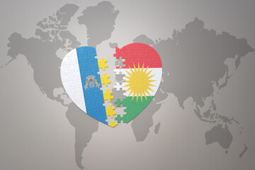 puzzle heart with the national flag of kurdistan and canary islands on a world map background.Concept.