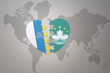 puzzle heart with the national flag of Macau and canary islands on a world map background.Concept.